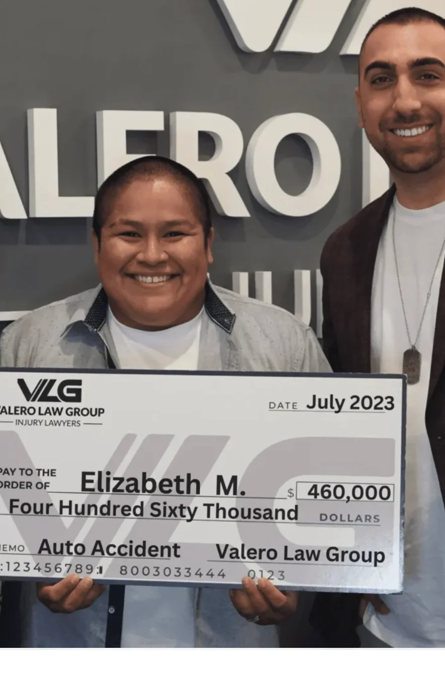 Valero Law Group client Elizabeth M. with attorney Kyle Valero, holding a $460,000 auto accident settlement check