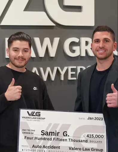 Valero Law Group client Samir G. with attorney Kyle Valero, holding a $415,000 auto accident settlement check