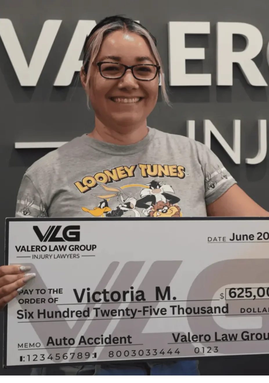 Cliente de Valero Law Group Victoria M. sosteniendo un cheque de acuerdo de $625,000 por accidente de auto